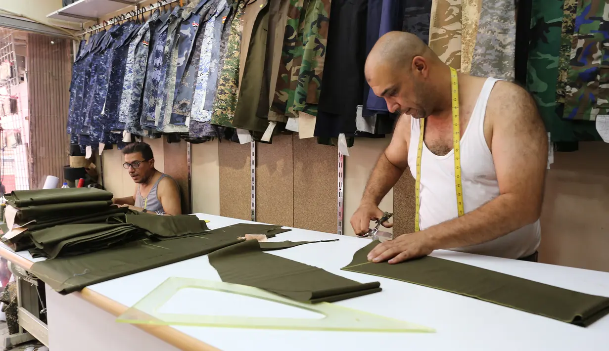 Penjahit Irak menyelesaikan pembuatan seragam militer di Baghdad (13/9). Perang yang berlangsung di Irak membuat para penjahit pakaian biasa kebanjiran orderan membuat seragam militer dan aksesorisnya. (AFP Photo/Sabah Arar)