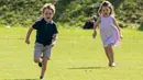 Pangeran George dan Putri Charlotte berlarian di atas rumput saat menghadiri acara amal Maserati Royal Charity Polo Trophy untuk mendukung sang ayah, Pangeran William yang bertanding di Beaufort Polo Club, Gloucestershire, Minggu (10/6). (AP Photo)