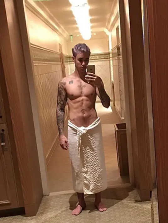 “Back in the gym.” tulis Justin Bieber di caption foto yang diunggahnya di akun instagram. Dirinya tak memakai apa pun selain handuk yang menggantung di pinggulnya dan sangat mengekspose perut seksinya itu. (via instagram/@justinbieber)