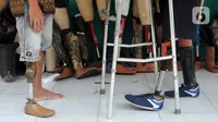 Ronald Regen (33), perajin yang juga penyandang disabilitas membantu pelanggan mencoba kaki palsu di Dusun IV Rawailat, Desa Dayeuh, Cileungsi, Bogor, Jawa Barat, Selasa (29/3/2022). UMKM kaki palsu yang sempat bangkrut akibat pandemi COVID-19 mulai bangkit sejak awal tahun.(merdeka.com/Arie Basuki)