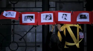 Seorang wanita menggantung foto korban kekerasan dalam rumah tangga saat memperingati Hari Internasional untuk Penghapusan Kekerasan terhadap Perempuan di Buenos Aires, Argentina, Rabu (25/11). (REUTERS/Marcos Brindicci)
