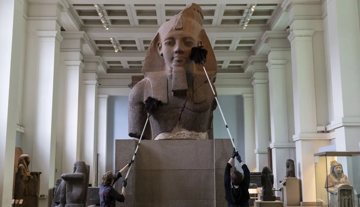 Sejumlah staf membersihkan debu pada permukaan sebuah benda pameran saat pratinjau media menjelang pembukaan kembali Museum Inggris di London, Inggris (25/8/2020). Museum tersebut akan dibuka kembali pada 27 Agustus. (Xinhua/Han Yan)