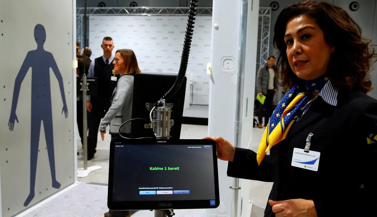 Petugas mengawasi calon penumpang yang hendak melewati Mesin deteksi full body terbaru Bandara Cologne-Bonn Konrad Adenaue, Jerman (15/11). Mesin ini akan secara otomatis mendeteksi benda-benda yang berpotensi bahaya. (REUTERS/Wolfgang Rattay)