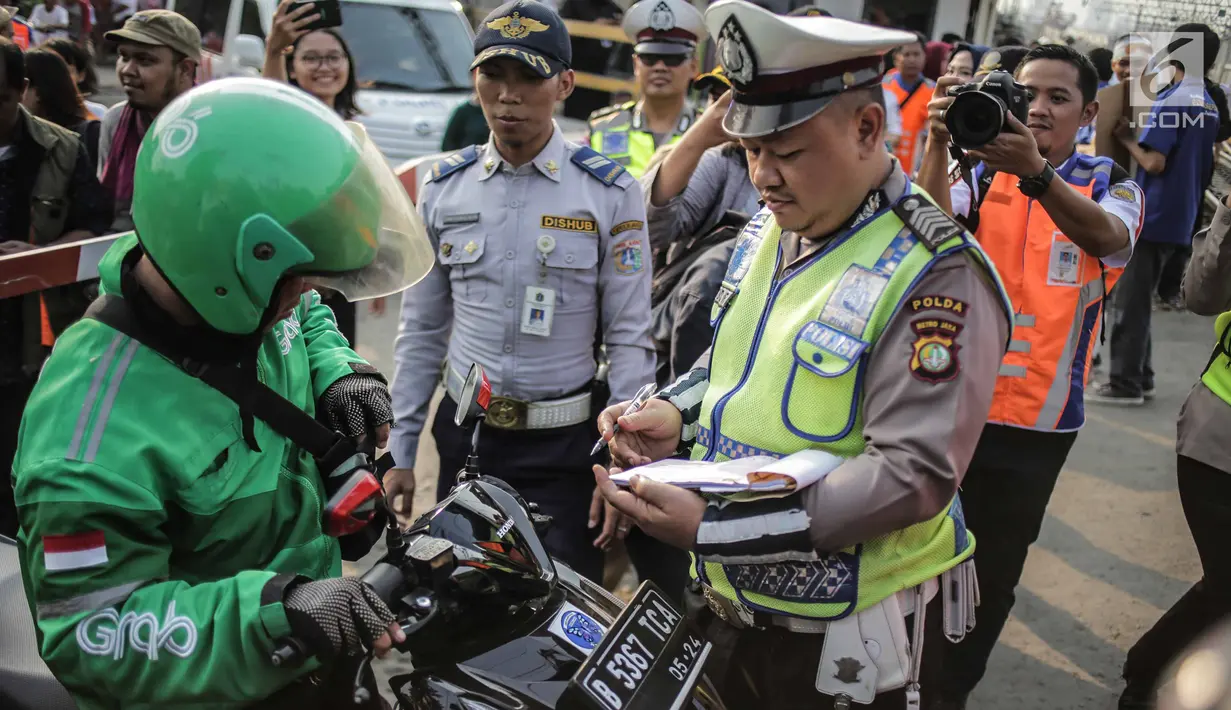 Polisi menilang pengendara saat petugas PT KAI Daop I menggelar sosialisasi tertib berlalu lintas di pintu perlintasan sebidang kawasan Bukit Duri, Jakarta, Selasa (17/9/2019). Sosialisasi dilakukan karena banyaknya kecelakaan akibat ketidakdisiplinan pengendara. (Liputan6.com/Faizal Fanani)