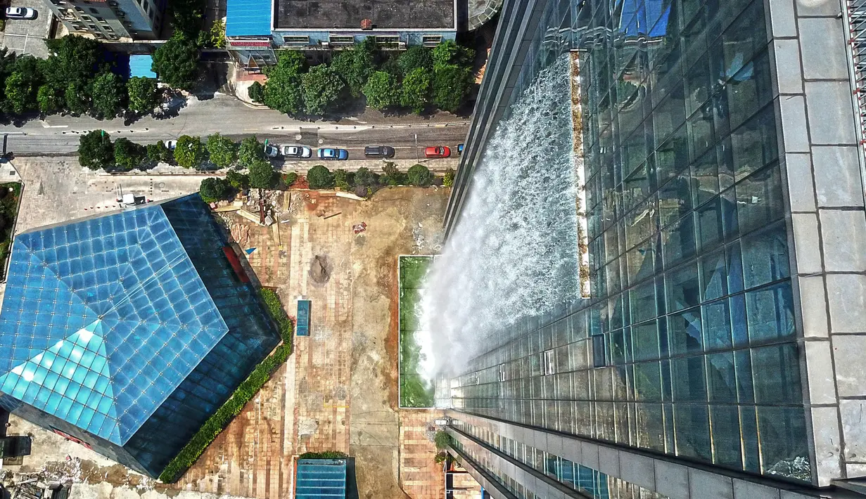 Air terjun buatan mengalir di sisi gedung pencakar langit Liebian International Plaza di Kota Guiyang, China, 20 Juli 2018. Air terjun itu hanya dioperasikan saat sedang ada acara khusus di gedungnya atau merayakan hari besar nasional. (AFP/China OUT)
