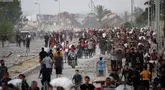 Warga Palestina berjalan di sepanjang jalan al-Rashid, Jabalia barat pada 23 Juli 2025, setelah menerima bantuan kemanusiaan dari titik distribusi bantuan di Jalur Gaza utara. (Eyad BABA/AFP)