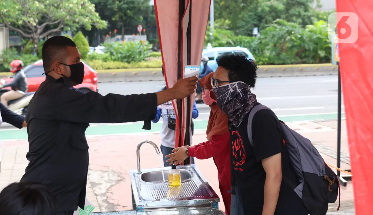 Petugas memeriksa suhu tubuh pengunjung saat hari pertama pembukaan kembali pusat kuliner Thamrin 10, Jakarta, Selasa (16/6/2020). Pemprov DKI Jakarta membuka kembali operasional 80 pusat perbelanjaan dengan menerapkan standar protokol kesehatan. (Liputan6.com/Angga Yuniar)