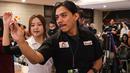 Dartslive Support Player asal Singapura Hedy Wong mengajarkan salah satu jurnalis yang mencoba alat di acara peluncuran Darts Station di lantai F7 FX Sudirman, Senayan, Jakarta pada Sabtu (15/11/2025). (Bola.com/Abdul Aziz)