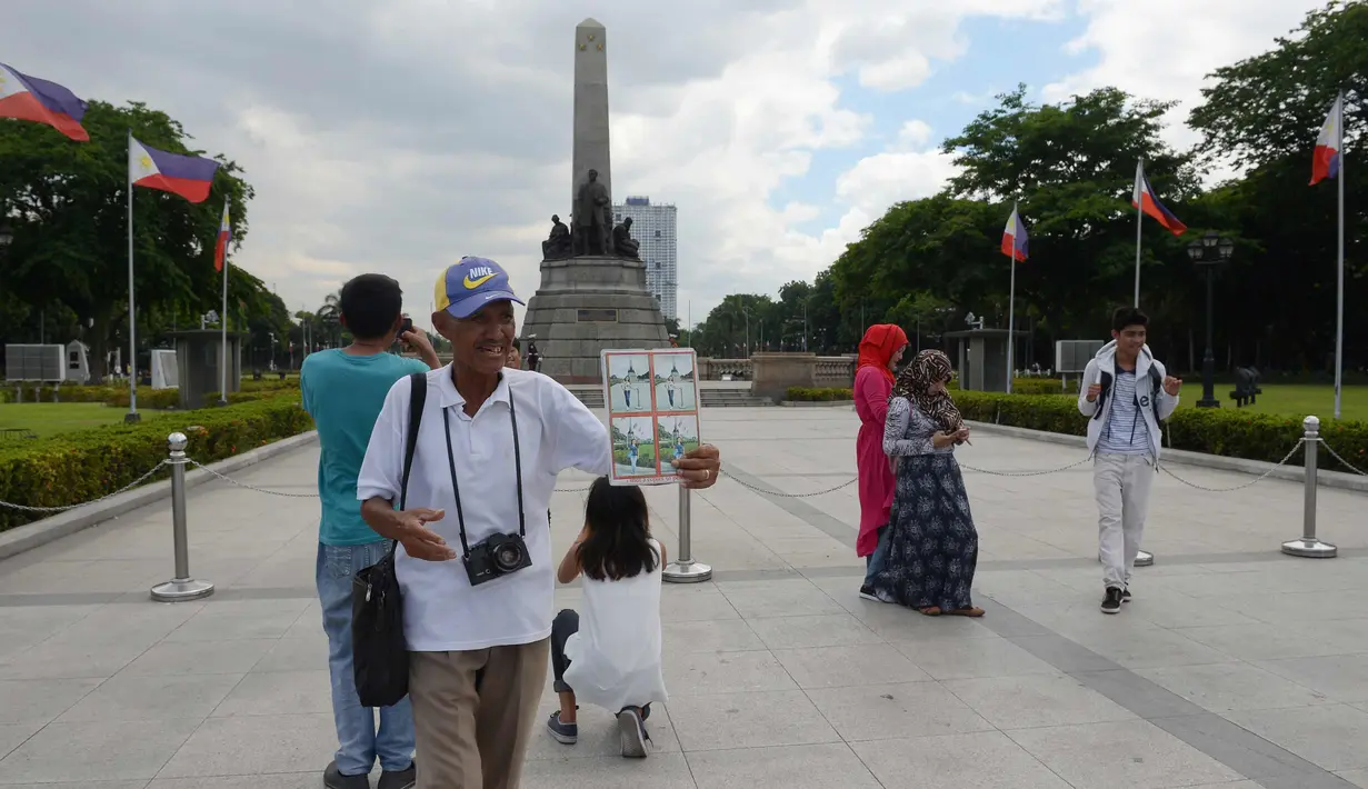 Joel Estrella menawarkan jasa foto kepada wisatawan di sebuah taman di Manila, (22/4). Estrella melihat penurunan pelanggan sejak munculnya ponsel kamera yang memotong penghasilannya ketika ia mulai sebagai fotografer muda. (AFP Photo/Ted Aljibe)