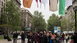 Pengunjung berswafoto di bawah seni instalasi jemuran pakaian raksasa di Paseo Bulnes, Santiago (2/10). Instalasi yang mirip jemuran tersebut bagian dari "Hecho en Casa Fest" (Made at Home Festival). (AFP Photo/Martin Bernetti)