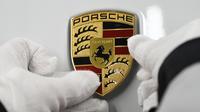 Mekanik memasang logo mobil listrik Porsche Taycan saat proses perakitan di pabrik perusahaan Porsche AG di Stuttgart, Jerman, Rabu (4/3/2020). Porsche Taycan merupakan mobil bertenaga listrik pertama  dari pembuat mobil mewah Jerman, Porsche AG. (AFP Photo/Thomas Kienzie)