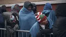 Para migran menunggu dalam cuaca dingin saat mereka mencari perlindungan di luar Pusat Bantuan Migran di Sekolah Dasar St. Brigid, New York pada Rabu, 29 November 2023. (AP Photo/Andres Kudacki)