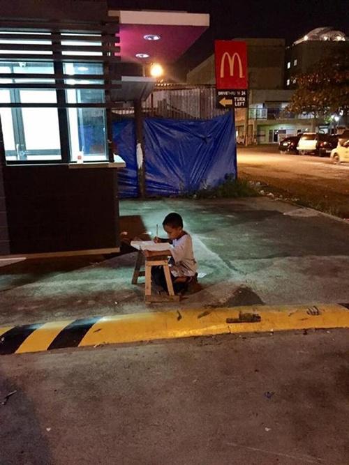 Daniel belajar di trotoar agar dapat lampu yang terang dari salah satu restoran cepat saji McDonald | Photo: Copyright yahoo.com