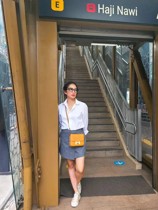 Gaya chic Ussy pakai kemeja lengan panjang berwarna putih, rok mini abu-abu, sneakers putih dan sling bag yang serasi. [Foto: Instagram/ussypratama]