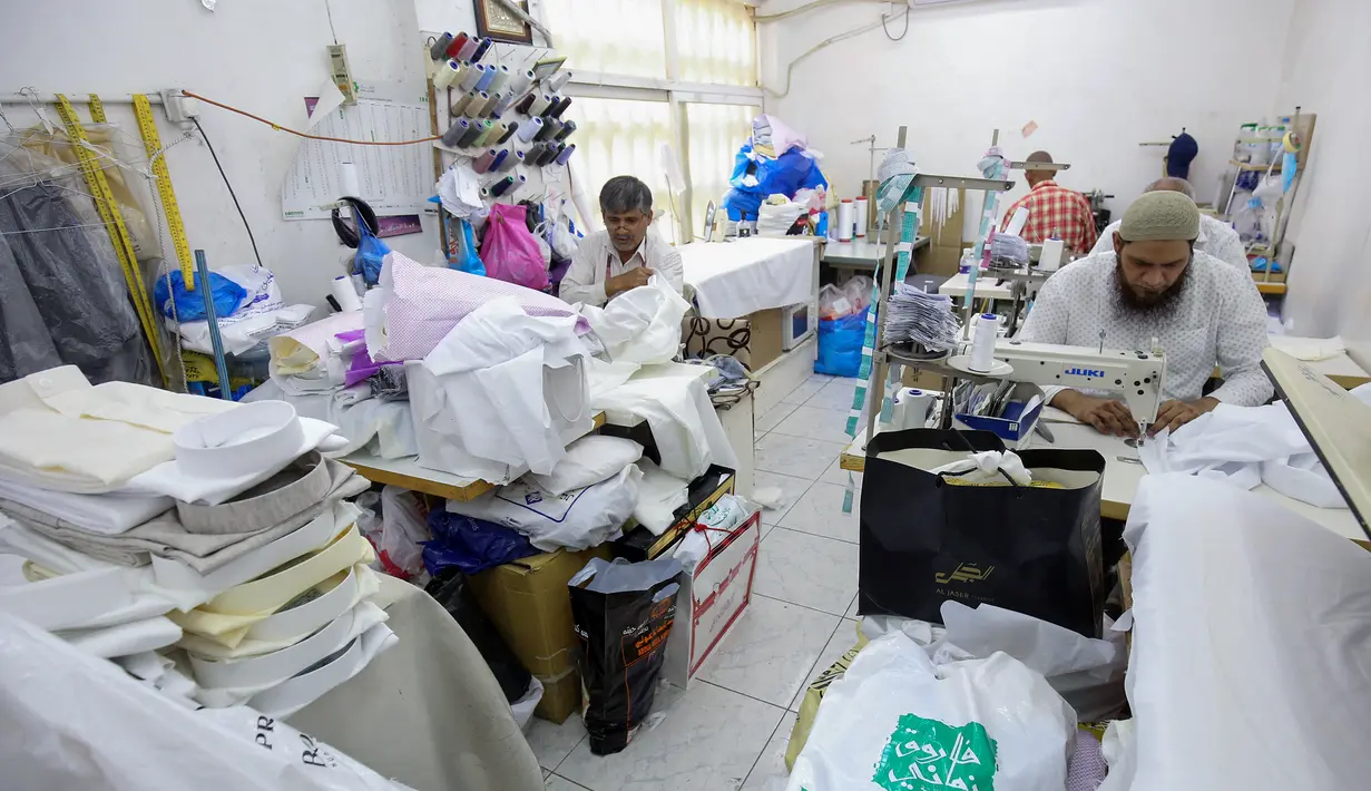 <p>Penjahit menyelesaikan produksi di tengah tingginya permintaan "dishdasha", pakaian tradisional Kuwait, di toko pakaian adat di Kuwait City pada 23 April 2022. Selama bulan suci Ramadhan dan Idul Fitri, pria dan anak laki-laki lebih suka memakai pakaian tradisional Kuwait. (YASSER AL-ZAYYAT / AFP)</p>