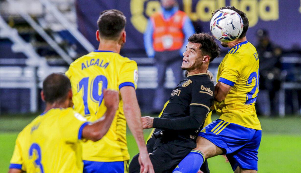 Penyerang Barcelona, Philippe Coutinho, duel udara dengan pemain Cadiz, Jairo Izquierdo, pada laga Liga Spanyol di Stadion Ramon Carranza, Minggu (6/12/2020). Barcelona takluk dengan skor 1-2. (AP/Alvaro Rivero)