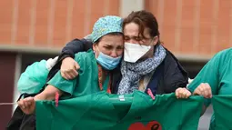 Petugas kesehatan (kiri) menenangkan istri Esteban, perawat yang gugur karena virus corona COVID-19 di Rumah Sakit Severo Ochoa di Leganes, Spanyol, Jumat (10/4/2020). Hingga Minggu (12/4/2020) pagi, total kasus COVID-19 di Spanyol sebanyak 163.027. (Photo by PIERRE-PHILIPPE MARCOU/AFP)