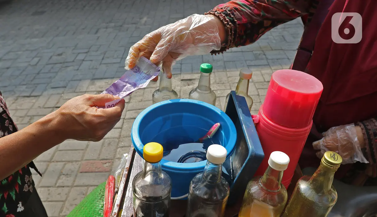 Tidar (46), melayani pembeli di Pasar Baru, Jakarta, Kamis (11/06/2020). Penjual jamu tradisional keliling ini tampak mematuhi protokol kesehatan pencegahan COVID-19 dengan mengenakan masker, face shield, dan sarung tangan dalam melayani pelanggan setianya. (Liputan6.com/Herman Zakharia)