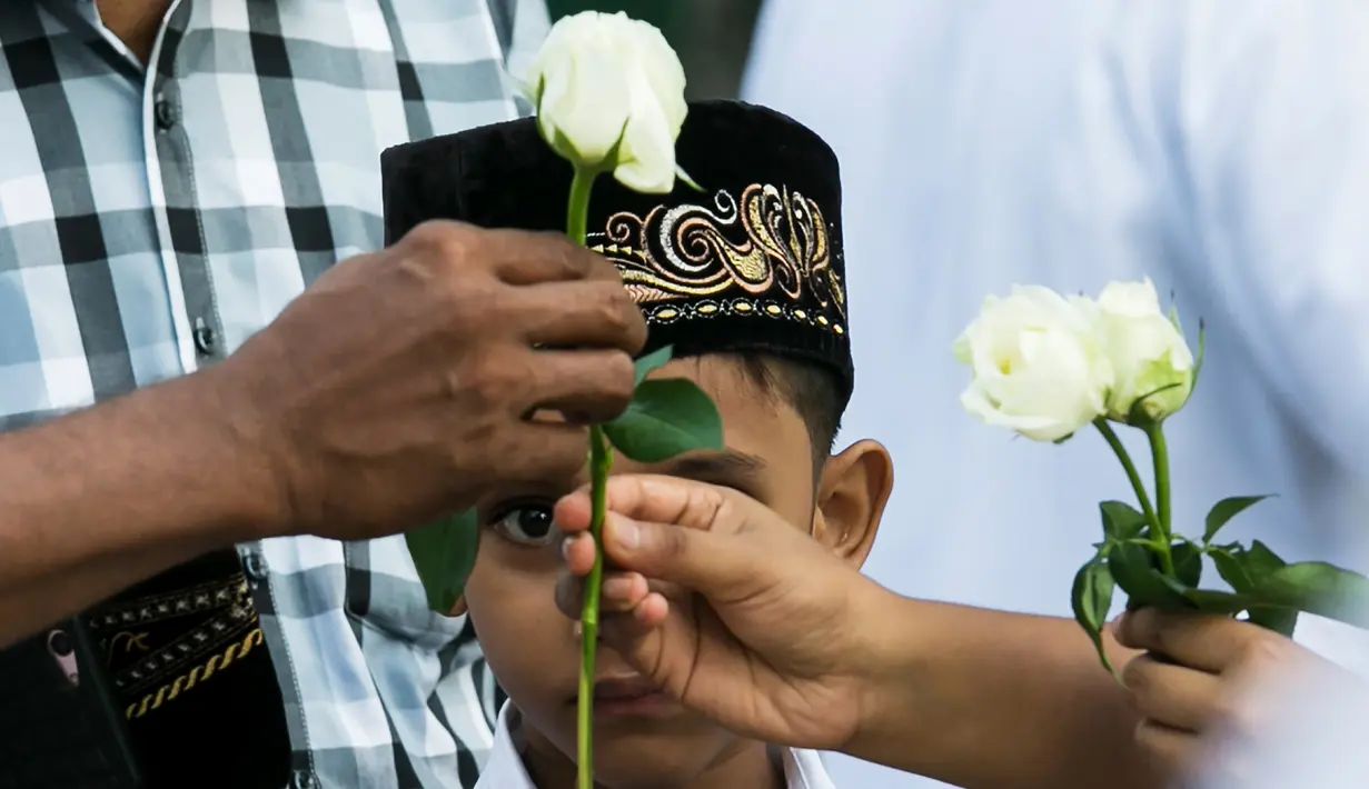 Umat Buddha Myanmar memberikan mawar putih kepada umat Islam yang akan melaksanakan salat Id pada perayaaan Idul Fitri di kota Than Lyin, pinggiran Yangon, Rabu (5/6/2019). Momen ini menjadi sebuah aksi solidaritas yang langka di sebuah negara, di mana Islam kerap difitnah.  (Sai Aung MAIN/AFP)