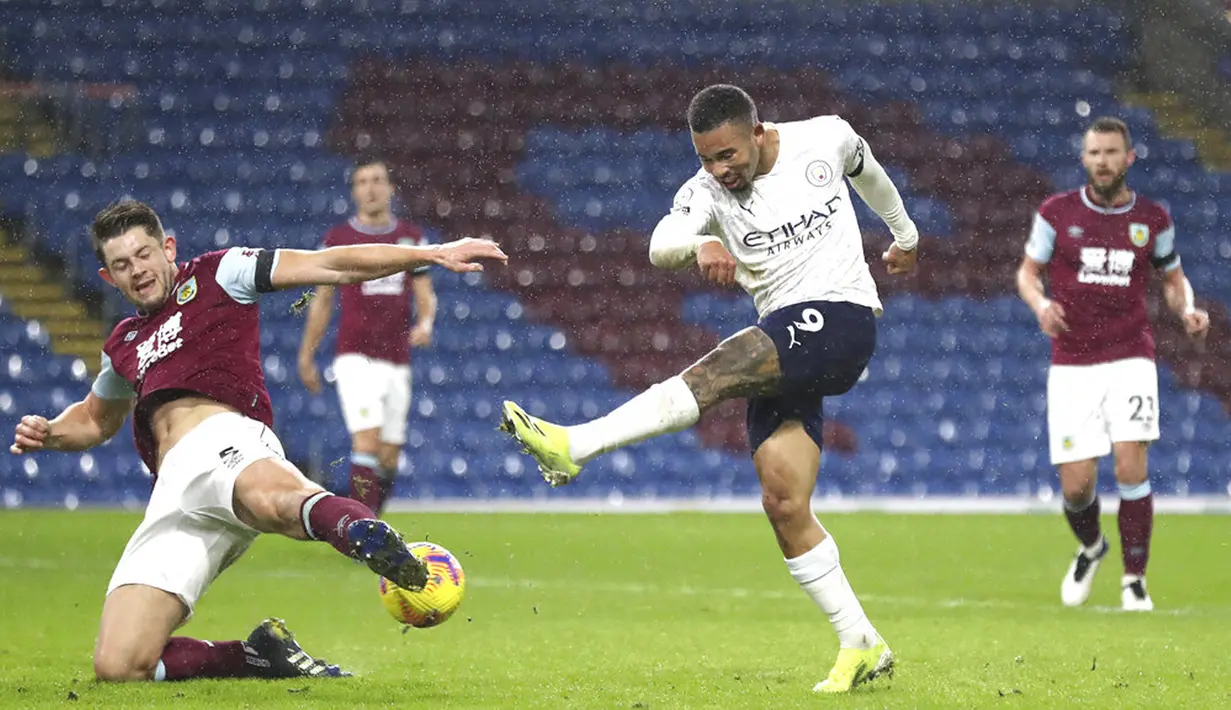 Pemain Manchester City Gabriel Jesus menendang bola di depan pemai Burnley James Tarkowski pada pertandingan Liga Inggris di Stadion Turf Moor, Burnley, Inggris, Rabu (3/2/2021). Manchester City menang 2-0. (Martin Rickett/Pool via AP)