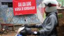 Pengendara motor melintas di depan poster protes warga terhadap pembangunan flyover di kawasan Tanjung Barat, Jakarta, Rabu (15/7/2020). Dalam poster protes tersebut, warga menuntut agar pembayaran pelunasan pembebasan lahan segera diselesaikan secara serentak. (Liputan6.com/Immanuel Antonius)