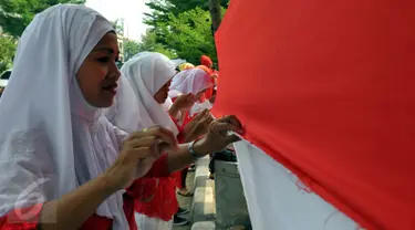 Sejumlah warga saat mengikuti lomba menjahit bendera Merah Putih sepanjang 500 meter di Kelurahan Pekojan, Jakarta, Minggu (16/8/2015). Lomba yg di ikuti oleh 12 RW dan 144 RT ini mengirimkan lima orang dlm setiap Rtnya. (Liputan6.com/Panji Diksana)