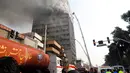 Petugas pemadam kebakaran berusaha menjinakkan api yang melahap gedung pencakar langit tertua Iran, gedung Plasco, di pusat kota Teheran, Kamis (19/1). Bangunan berlantai 15 itu runtuh menyusul kebakaran hebat yang terjadi. (AFP PHOTO/STR)