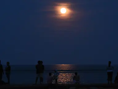 Warga mengamati keindahan supermoon yang terlihat di atas Pantai Sanur, Bali, Senin (14/11). Fenomena ini terjadi saat bulan mencapai titik terdekat dengan bumi dan merupakan fenomena supermoon terbesar dalam 68 tahun terakhir. (SONNY TUMBELAKA/AFP)