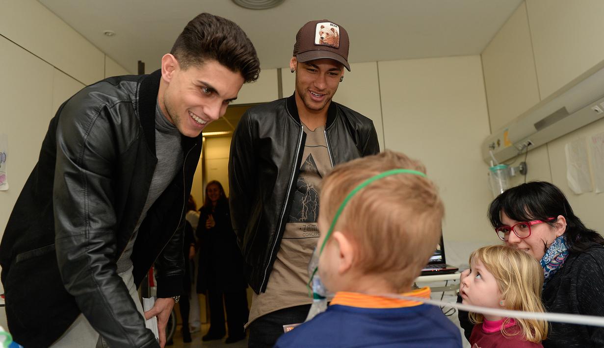Pemain Barcelona, Marc Bartra (kiri) dan Neymar berbincang dengan salah satu pasien anak saat melakukan kunjungan amal di Rumah Sakit Vall d' Hebron, Barcelona, Senin (4/1/2016). (AFP PHOTO / Josep LAGO)