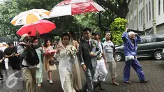 Sejumlah orang dari ormas islam memayungi sepasang mempelai yang akan melangsungkan pernikahan di Gereja Katedreal, Sabtu (11/2). (Liputan6.com/Herman Zakharia)