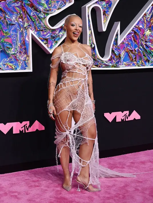 Doja Cat tiba di karpet merah MTV VMA mengenakan gaun putih rajutan dari Monse dengan detail seperti jaring laba-laba. Dia melengkapi ansambelnya dengan perhiasan berlian dari Maria Tash dan Nicole Rose. [@upscalemagazine]