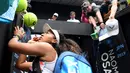 Petenis Jepang Naomi Osaka menandatangani benda yang disodorkan penonton usai mengalahkan petenis Republik Ceko Marie Bouzkova pada Australia Terbuka di Melbourne, Australia, Senin (20/1/2020). Penonton menyodorkan topi, bendera, hingga bola untuk ditandatangani Naomi. (AP Photo/Andy Brownbill)