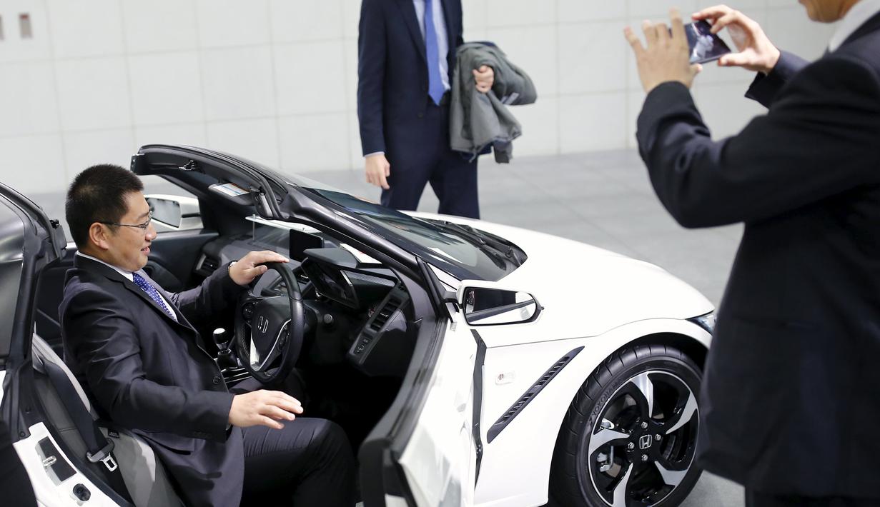 Seorang pria mencoba mobil Honda S660 di markas besar Honda Motor Co di Tokyo, Jepang, (24/2). Mobil berbobot kira-kira 830kg dengan transmisi manual dan 850kg dengan CVT otomatis. (REUTERS/Thomas Peter)