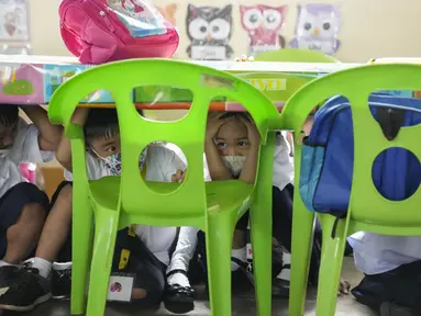 Siswa menunduk di bawah meja selama latihan gempa di sebuah sekolah dasar di Metro Manila, Filipina, Kamis (8/9/2022). Filipina melakukan latihan gempa nasional kuartal ketiga sebagai bagian dari upaya untuk membuat publik mengetahui protokol dan tanggapan selama bencana. (AP Photo/Aaron Favila)
