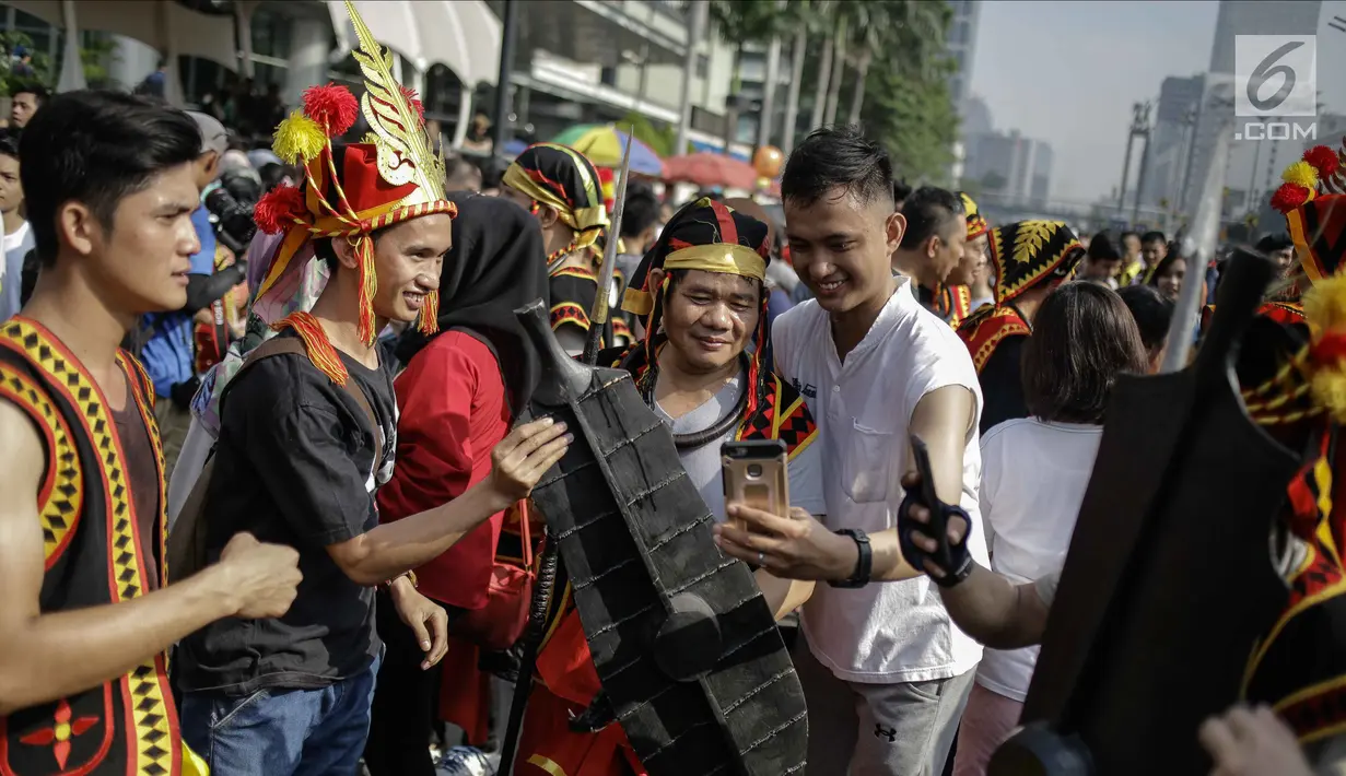 Warga berfoto bersama dengan mengenakan atribut budaya Kepulauan Nias saat CFD di Kawasan Jalan Sudirman, Jakarta, Minggu (4/3). Warga antusias dengan acara parade ini, karena mereka bisa menjajal pakaian adat Kepulauan Nias. (Liputan6.com/Faizal Fanani)