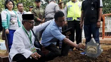 Seorang ulama (kiri) dan Iwan Setiawan, saudara laki-laki terpidana mati Zainal Abidin, saat prosesi pemakaman di TPU di Cilacap, Jateng, Rabu (29/4). Zainal satu-satunya terpidana mati asal Indonesia yang dieksekusi dini hari ini. (REUTERS/Beawiharta)