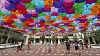 Pengunjung melewati instalasi Umbrella Sky Project di Aix-en-Provence, Prancis, Jumat (28/6/2019). Spot berteduh yang instagramable tersebut merupakan karya seniman Portugis Patricia Cunha. (BORIS HORVAT/AFP)
