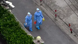 Petugas kesehatan yang mengenakan alat pelindung diri (APD) berjalan di jalan setelah meninggalkan lingkungan saat lockdown akibat virus corona COVID-19 di Distrik Jing'an, Shanghai, China, Sabtu (16/4/2022). (Hector RETAMAL/AFP)
