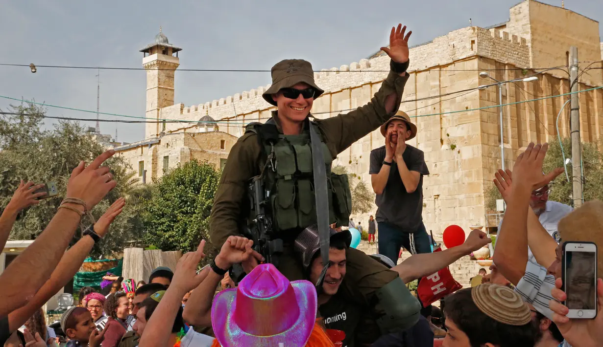 Warga Yahudi mengangkat seorang tentara saat merayakan Hari Purim di Jalan al-Shuhada, Kota Hebron, Tepi Barat, Kamis (1/3). (AFP PHOTO/HAZEM BADER)