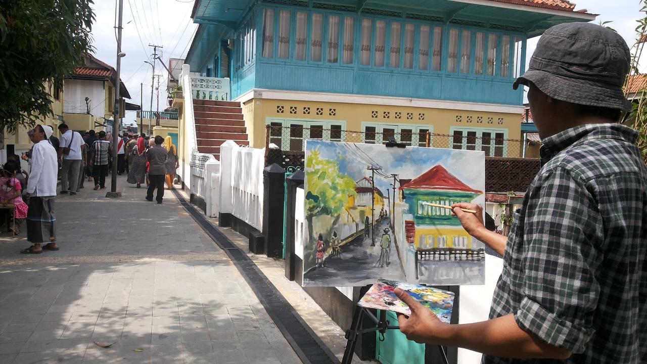 Pelukis di Palembang menggambarkan suasana Kampung Arab Al-Munawar Palembang dikertas kanvas (Liputan6.com/Nefri Inge)
