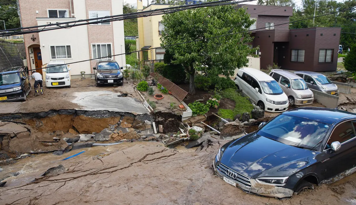 Sebuah mobil terjebak di jalan yang rusak akibat gempa mengguncang Sapporo di prefektur Hokkaido, pada Kamis (6/9). Gempa magnitudo 6,7 yang mengguncang Hokkaido kemudian memicu tanah longsor. (Hiroki Yamauchi/Kyodo News via AP)