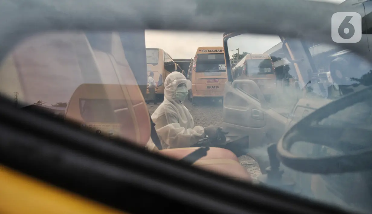 Petugas Kebersihan Bus (PKB) melakukan pengasapan antibakteri pada bus sekolah di Pool Unit Pelayanan Angkutan Sekolah (UPAS) DKI Jakarta, Kramat Jati, Selasa (5/1/2021). Sterilisasi bus sekolah dilakukan usai digunakan mengangkut pasien terpapar Covid-19 ke RS rujukan. (merdeka.com/Iqbal Nugroho)