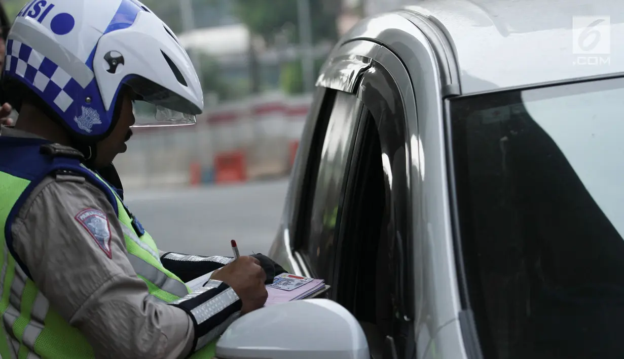 Polisi memberikan surat tilang kepada pengemudi mobil yang melanggar sistem ganjil genap di Jalan MT Haryono, Jakarta, Rabu (1/8). Hari pertama pemberlakuan sistem ganjil genap, pelanggar dikenakan sanksi Rp 500 ribu. (Merdeka.com/Iqbal S. Nugroho)