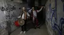 Dua pemuda "Musharati" Palestina memukul gendang saat membangunkan umat muslim untuk sahur pada malam kedua selama bulan suci Ramadan di Rafah di Jalur Gaza selatan (25/4/2020). (AFP/Said Khatib)