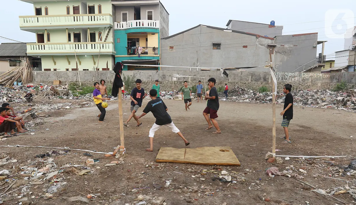 Sejumlah warga bermain sepak bola di antara tumpukan sampah di kawasan Penjaringan, Jakarta, Jumat (1/11/2019). Minimnya lahan bermain di Jakarta membuat warga bermain sepak bola di sekitar tumpukan sampah. (Liputan6.com/Herman Zakharia)