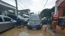 Seorang petugas penyelamat membantu warga saat mereka berjalan melewati mobil-mobil yang tersapu banjir pada puncak Topan Kalmaegi di sebuah permukiman di Kota Cebu, Filipina tengah, pada Selasa 4 November 2025. Sejumlah warga dilaporkan terjebak di atap rumah akibat naiknya air, sementara puluhan kendaraan terendam. (Alan TANGCAWAN/AFP)