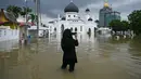Faktor-faktor lain terkait lahan seperti perubahan penggunaan lahan, kepadatan populasi, dan efektivitas sistem drainase lokal ikut memengaruhi terjadinya bencana banjir di Malaysia. Tampak dalam foto, seorang perempuan mengambil dokumentasi masjid yang terendam banjir di Kangar, negara bagian Perlis, Malaysia utara, pada Kamis 27 November 2025. (Mohd RASFAN/AFP)