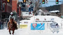 Joki yang bernama Zach West menarik pemain ski salju Greg Dahl yang melompat saat mengikuti kompetisi Leadville Ski Joring ke-70 di Leadville, Colorado (4/3). (AFP Photo/Jason Connolly)