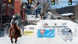 Joki yang bernama Zach West menarik pemain ski salju Greg Dahl yang melompat saat mengikuti kompetisi Leadville Ski Joring ke-70 di Leadville, Colorado (4/3). (AFP Photo/Jason Connolly)