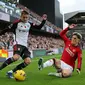 Gelandang Manchester United, Alejandro Garnacho, berusaha menghalau tendangan bek Fulham, Timothy Castagne, pada laga pekan ke-11 Premier League 2023/2024 yang digelar di Craven Cottage, Sabtu (4/11/2023) malam WIB. (AFP/Adrian Dennis)